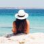 Woman Sitting on a White Sand Beach.